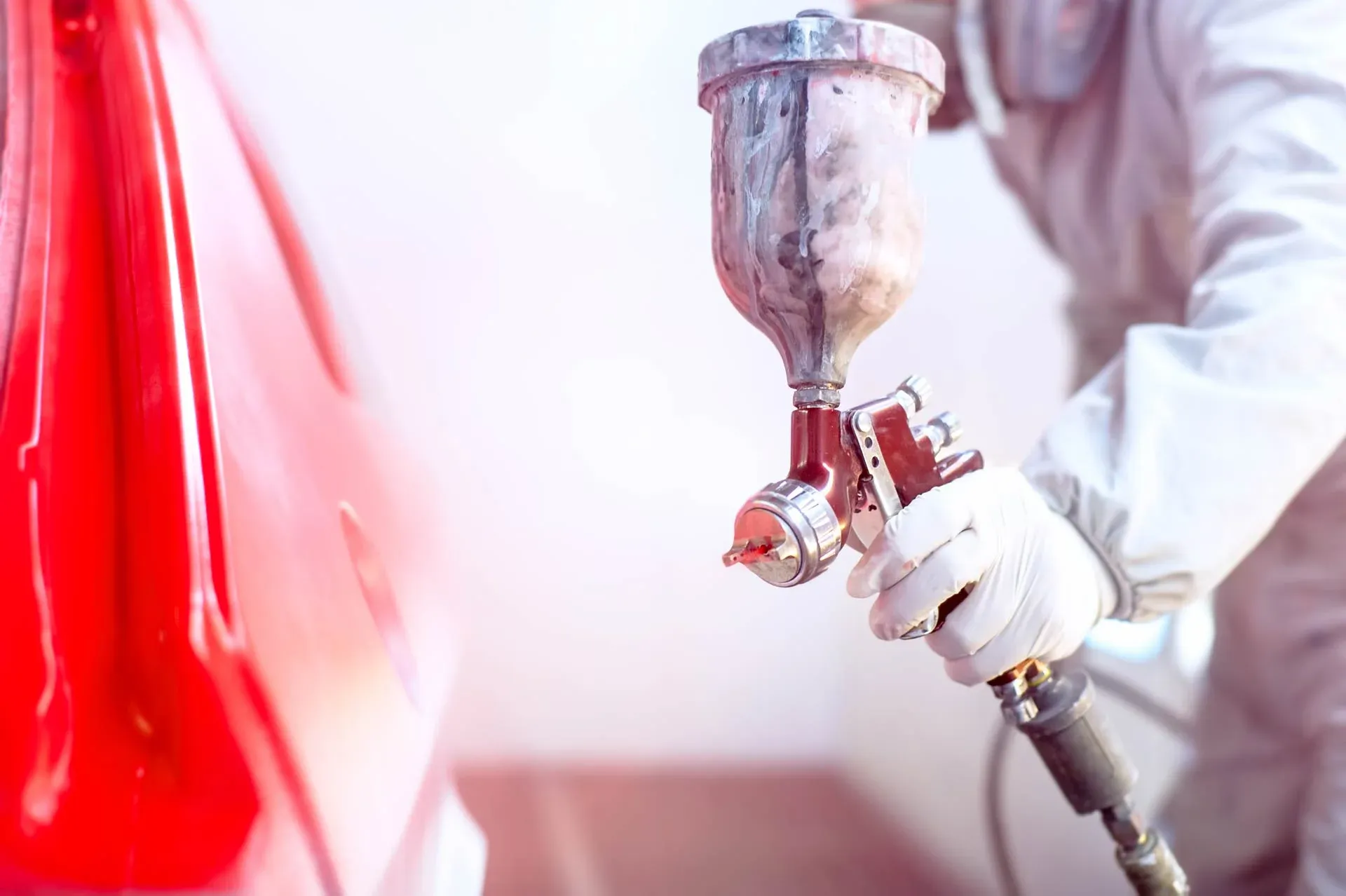 Spray gun applying red car paint at Direct Finish York